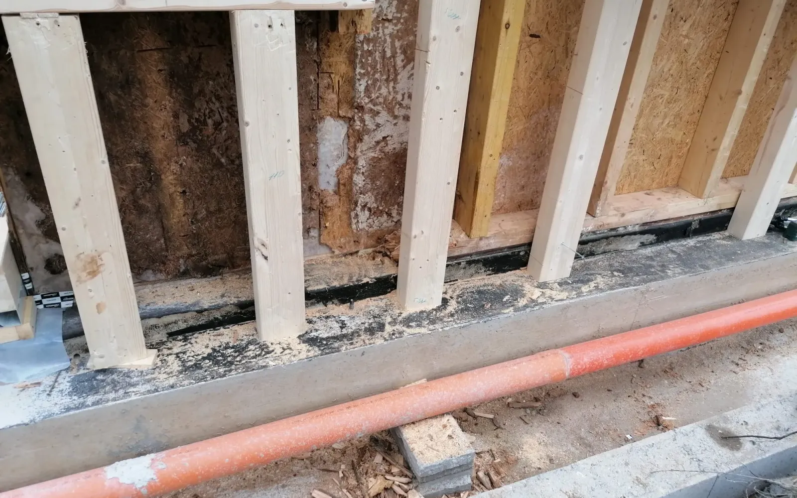 Struttura in legno danneggiata accanto alla nuova struttura in fase di ripristino.