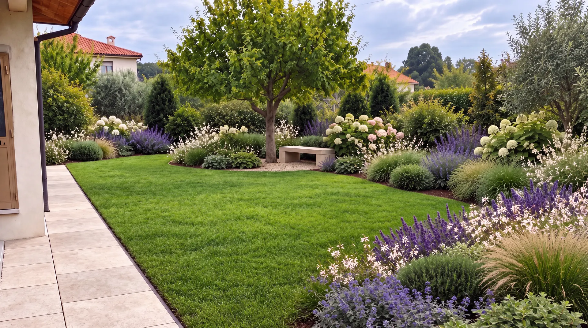 Giardino rinnovato con prato rigenerato, bordure fiorite e alberi esistenti valorizzati nel nuovo progetto.